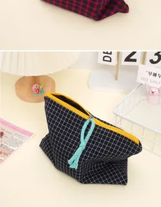 Detail of blue plaid makeup bag showing yellow zipper and light blue woven rope puller