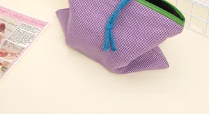 Detail of purple plaid pouch featuring green zipper and blue decorative rope tie