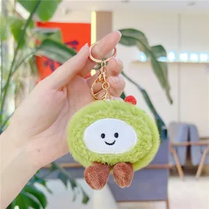 Detailed close-up of a green plush avocado keychain with golden metal clasp held in hand