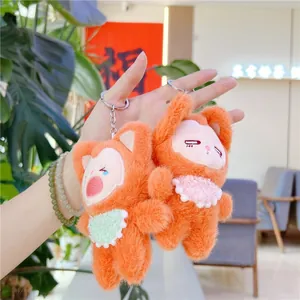 Close-up of two orange plush fox keychains with bibs and silver metal rings