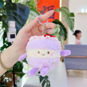 Nahaufnahme von Plüschkuchen-Taschenanhänger in der Hand mit flauschiger lila Textur und Gesicht