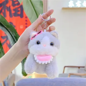Close-up of a cute plush cat keychain with pink sunglasses and a metal ring clip