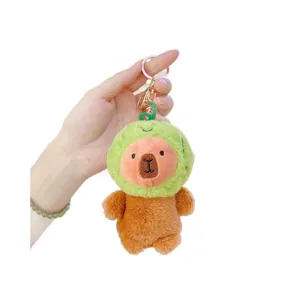 Plush capybara keychain wearing a green turtle costume being held for size perspective