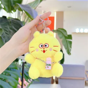 Detailed view of yellow plush cat keychain with embroidered face and pink milk bottle charm