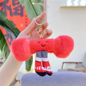 Close-up of a cute red dumbbell-shaped plush keychain with smiling face and mini sneakers