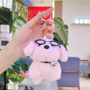 Close-up of pink plush dog keychain with black glasses and golden metal ring detail