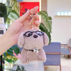 Macro view of plush dog keychain with round glasses, silver bell and golden hook