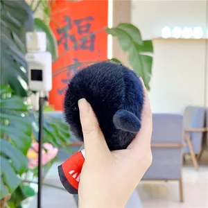Close-up of a soft black plush dumbbell keychain with red and white fabric details
