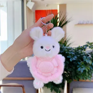 Primer plano de un llavero de conejo de peluche con mochila rosa sostenido con la mano