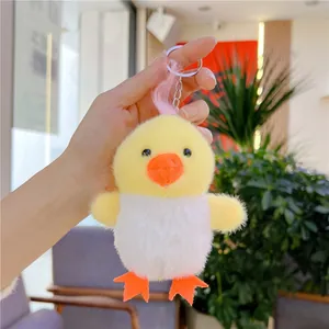 Close-up of fluffy yellow and white chicken plush keychain with pink hair and metal ring