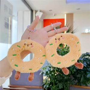 Plush donut keychain with cute smiling face and colorful embroidery held in hand