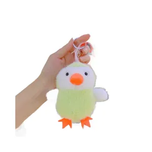 Cute green plush chick keychain doll for bag decoration held in hand on white background