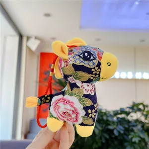 Detail of blue floral Chinese zodiac horse plush toy with yellow accents and red cord