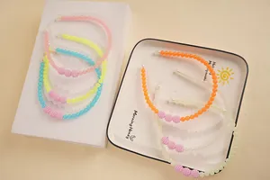 Macro detail of macaron beaded headbands with frosted pink accent beads on white trays