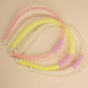 Detailed close-up of four colorful beaded headbands in pink, yellow, and white pearls