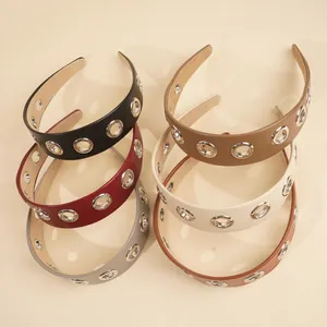 Flat lay of wide PU leather headbands in six colors with silver hollow eyelet details
