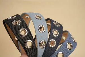 Close-up of denim headbands featuring large silver metal eyelets and textured twill fabric