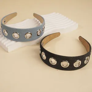 Denim wide headbands with silver metal eyelets in blue and black colors on a wavy stand