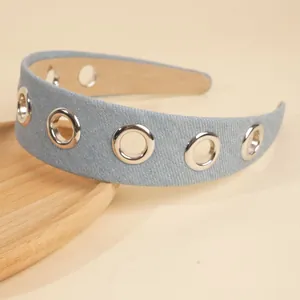 Detail of light blue denim headband with silver metal eyelets on a wooden tray