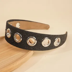 Detail of black denim headband with large silver metal grommets on a wooden tray