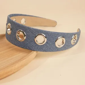 Detail of blue denim headband with silver metal eyelets on a wooden display tray