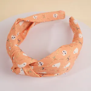 Détail d'un serre-tête d'Halloween orange avec motifs de fantômes et de crânes
