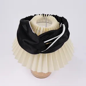 Detail view of black silk headband with white contrast piping and elastic back band