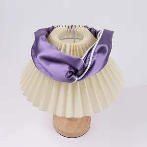 Detail of a deep purple satin headband with white piping on a pleated lamp shade