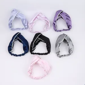 Flat lay of satin twisted headbands in seven colors with elegant white piping and elastic back