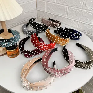 Fashion velvet knot headbands with pearl beads in assorted colors on a white table