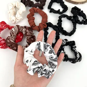 Set di elastici per capelli in tessuto con motivi paisley e tinte unite su sfondo bianco