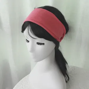 Close-up of a wide coral pink elastic headband worn by a model for yoga and sports