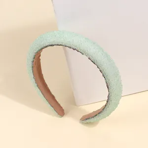 Dettaglio di un cerchietto spesso verde chiaro con perline fitte e fodera interna marrone