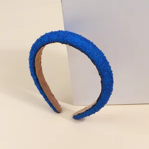 Dettaglio ravvicinato di un'ampia fascia per capelli con perline blu e trama luccicante