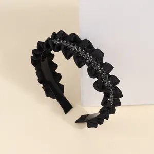 Detailed close-up of a pleated black headband featuring sparkling crystals and a toothed inner grip