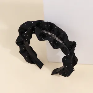 Macro shot of pleated black satin headband with sparkling crystals and silver sequins
