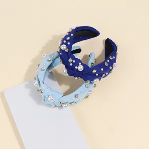 Detail of baroque pearl and rhinestone knots on navy and light blue fabric headbands