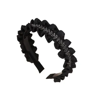 Macro shot of black pleated fabric headband with shiny dark grey rhinestones detailing