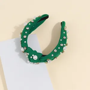 Close-up of green knotted headband featuring baroque pearls and sparkling rhinestones
