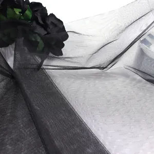 Detail of delicate black mesh veil featuring artificial dark roses and green leaves