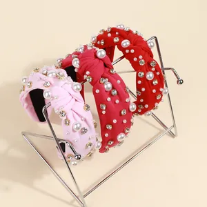 Close-up of wide knotted headbands with pearls and rhinestones in pink and red colors
