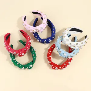 Detailed overhead view of six colorful knotted headbands with pearls and rhinestones