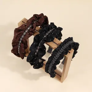 Sparkling crystal ruffle headbands in brown and black on a wooden display stand