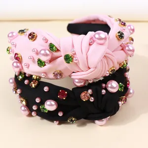 Close-up of knotted fabric headbands with pink pearls and colorful gemstone rhinestones