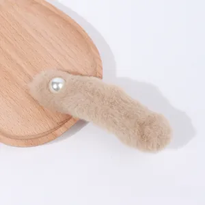 Dettaglio di una grande pinza per capelli in peluche marrone con perla su vassoio