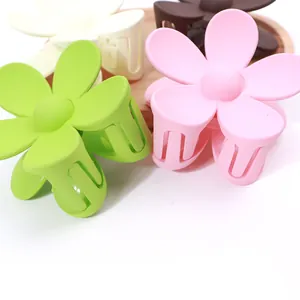 Dettaglio di fermagli per capelli a forma di fiore opaco in vari colori su vassoio di legno