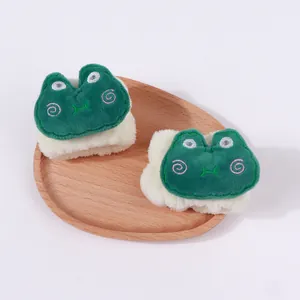 Nahaufnahme süßer grüner Frosch-Plüsch-Armbänder in einer Holzschale zum Gesichtswaschen