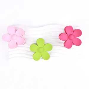 Tre mollette a fiori opachi in rosa e verde presentate su una base bianca strutturata