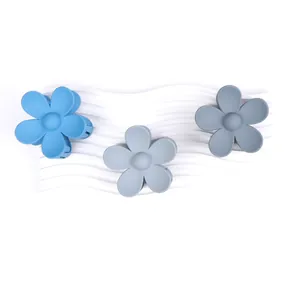 Set di tre mollette per capelli a fiore opaco blu su un display bianco ondulato