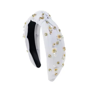 Close-up of white knotted headband featuring 3D flowers, pearls, and rhinestones